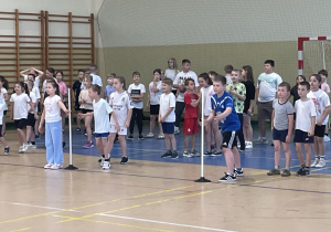 Uczniowie stoją w hali gotowi do rozgrywek sportowych.