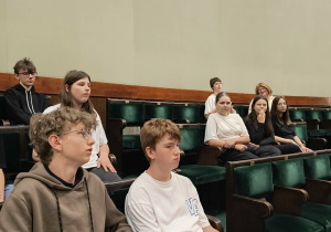 Uczniowie siedzą na sali obrad sejmu.