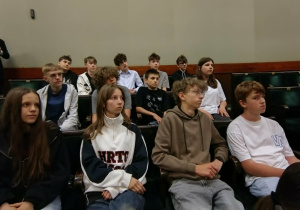 Siódmoklasiści siedzą w fotelach poselskich w sali sejmowej.