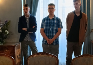 Uczniowie stoją w jednej z sal Pałacu Prezydenckiego.