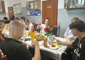 Chłopcy siedzą przy stole i jedzą.