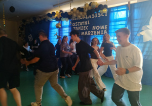 Uczniowie klas ósmych tańczą.