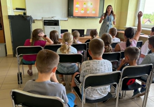 Dzieci siedzą podczas spotkania z pracownicą sanepidu.