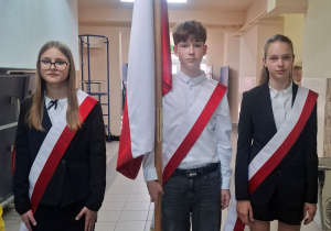 Nowi członkowie pocztu flagowego stoją z flagą państwową.