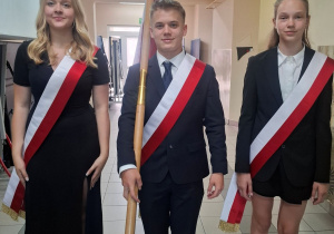 Ustępujący członkowie pocztu flagowego stoją z flagą.