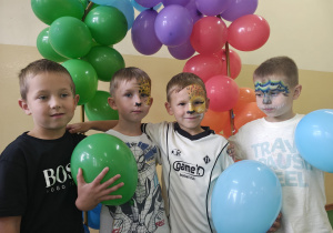 Chłopcy z pomalowanymi buziami trzymają balony.