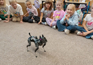 Przedszkolaki patrzą na chodzącego robota.