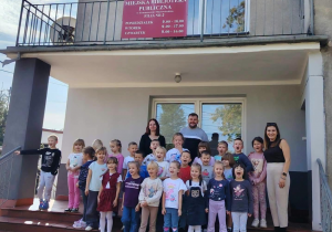 Przedszkolaki stoją przed wejściem do filii nr 2 MBP z opiekunem i organizatorami.