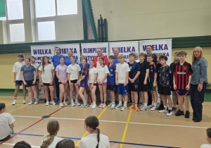 Uczniowie klas siódmych stoją z Olimpijczykami i organizatorami imprezy.