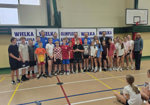 Szóstoklasiści stoją z Olimpijczykami i organizatorami imprezy.