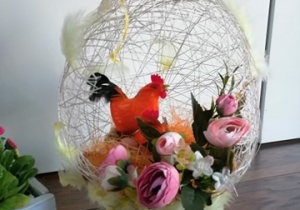 Białe jajko ze sznurka z różowymi kwiatami i kogucikiem