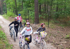 Zmęczone dziewczynki z klasy VIc z panią M. Kubaszewską prowadzą rowery przez las