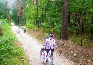 Dziewczynki z klasy VIc prowadzą rowery leśną ścieżką