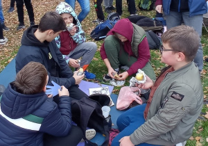 Uczniowie jedzą upieczone w ognisku ziemniaki