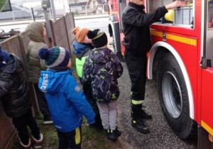 Strażak z OSP pokazuje chłopcom samochód straży