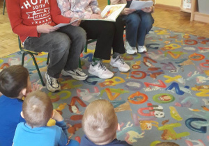Uczniowie czytają bajkę dzieciom w przedszkolu