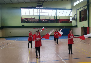 Układ z flagami prezentują uczennice klasy czwartej i piątej