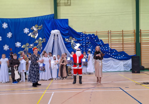 Mikołaj rozdaje prezenty uczniom razem z p. Dorotą Wieczorek oraz p. Dyrektor Elżbietą Wilczyńską