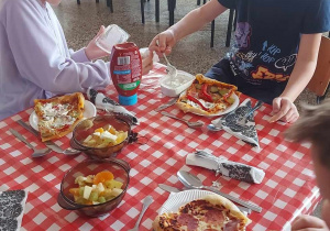 Dzieci zajadają własnoręcznie przyrządzone pizze