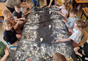 Dzieci formują z ciasta zajączki i baranki