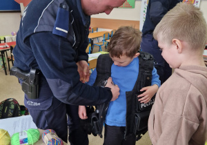 Dzieci przymierzają kamizelkę policyjną