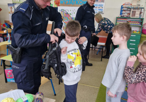 Dzieci kolejno przymierzają kamizelkę policyjną
