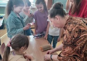 Pani bibliotekarka pokazuje uczniom jak wykonać kota ze starych książek