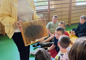 Pani Renata pokazuje dzieciom plaster miodu