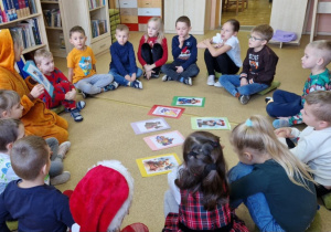 Pani bibliotekarka przedstawia dzieciom misie- bohaterów książek i filmów.