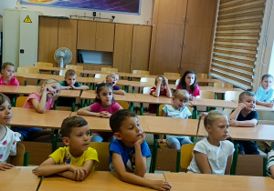 Dzieci przypatrują się jak Pani wykonuje doświadczenie chemiczne.
