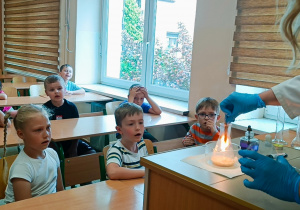 Nauczyciel chemii wykonuje doświadczenie, a dzieci patrzą.