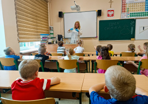 Pani Monika Kamińska wykonuje doświadczenie chemiczne przed dziećmi.