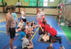 Dziewczyny z młodzieżowej drużyny strażackiej pokazują na fantomie masaż serca.