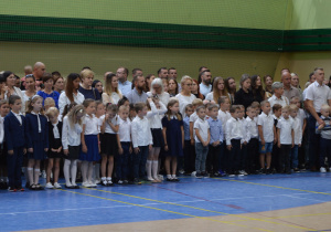 Uczniowie klas pierwszych i dzieci z grupy "0" z wychowawcami i rodzicami w hali sportowej