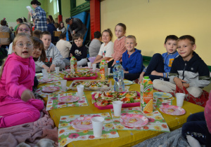 Klasa IIb siedzi przy zaaranżowanym stole z kanapkami.