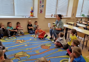 Dzieci siedzą w kole podczas rozmowy z panią psycholog.
