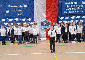Chłopiec z klasy pierwszej stoi podczas swojego wystepu.