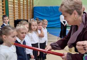 Pani Dyrektor Wydziału Edukacji Urzędu Miasta pasuje pierwszoklasistkę na uczennicę Szkoły Podstawowej nr 6.