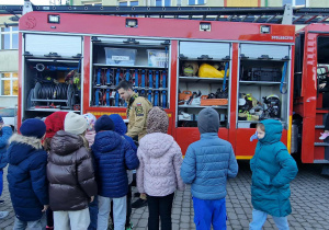 Uczniowie oglądają wyposażenie wozu strażackiego.