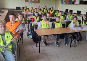 Uczniowie Va w kamizelkach siedzą w pracowni informatycznej.