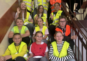Klasa Vb w kamizelkach odblaskowych stoi na schodach.