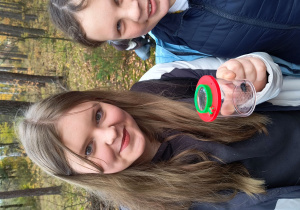 Dziewczynki pokazują żuka złapanego do pojemnika.