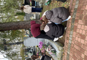 Uczniowie sprzątają wokół grobu.