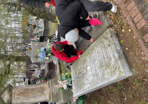 Chłopcy robią porządki przy grobie.