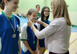 Dyrektor Elżbieta Wilczyńska zakłada dziewczętom medale.
