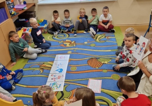 Pani bibliotekarka prowadzi zajęcia z grupą "0" na dywanie.